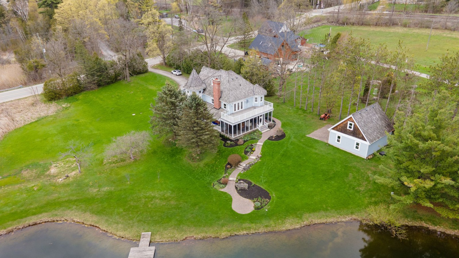 Aerial view of a completed Northern Vibe property: curved mulch beds, a stone pathway and lawn running down to the water.