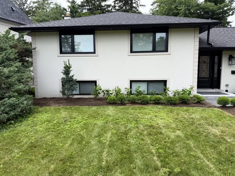 The same frontage from the side, hedging running the length of the house over fresh mulch.