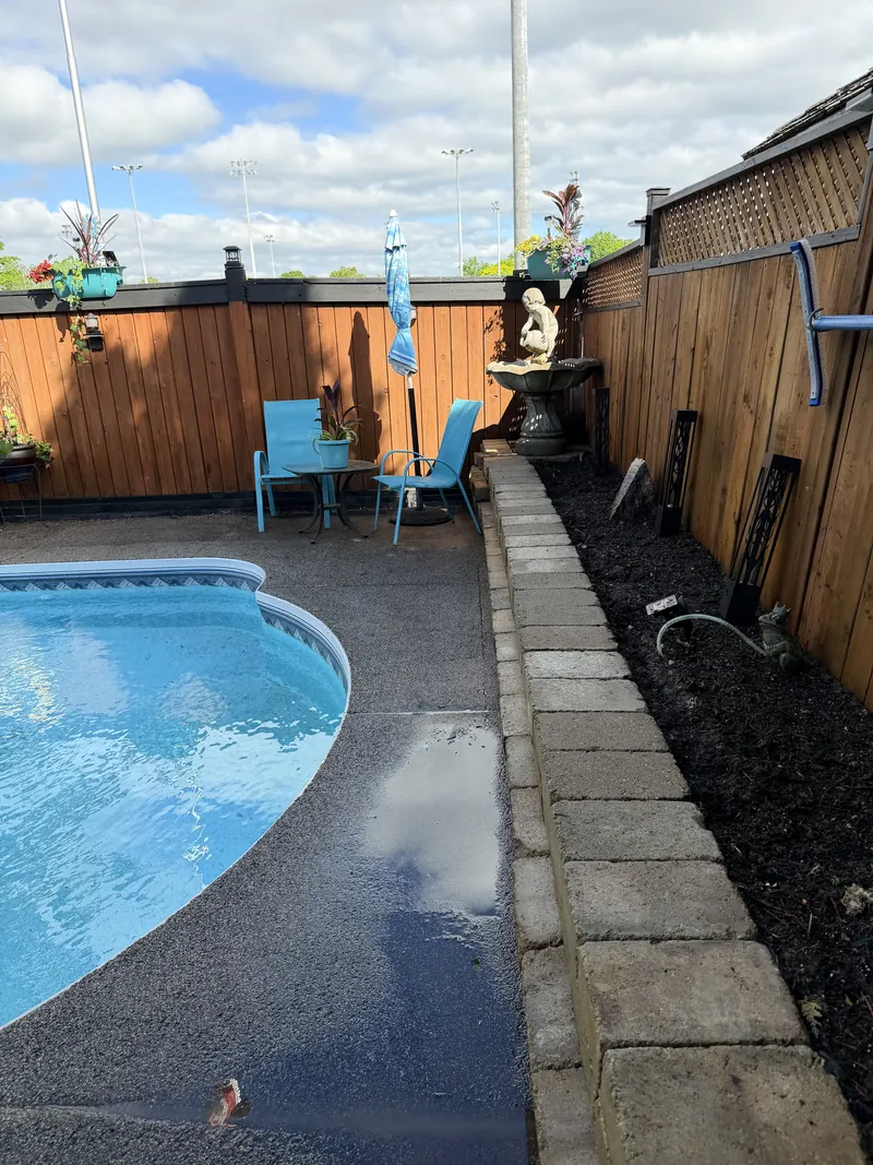 The finished strip: stone edging laid along the fence with a clean mulch bed behind it.